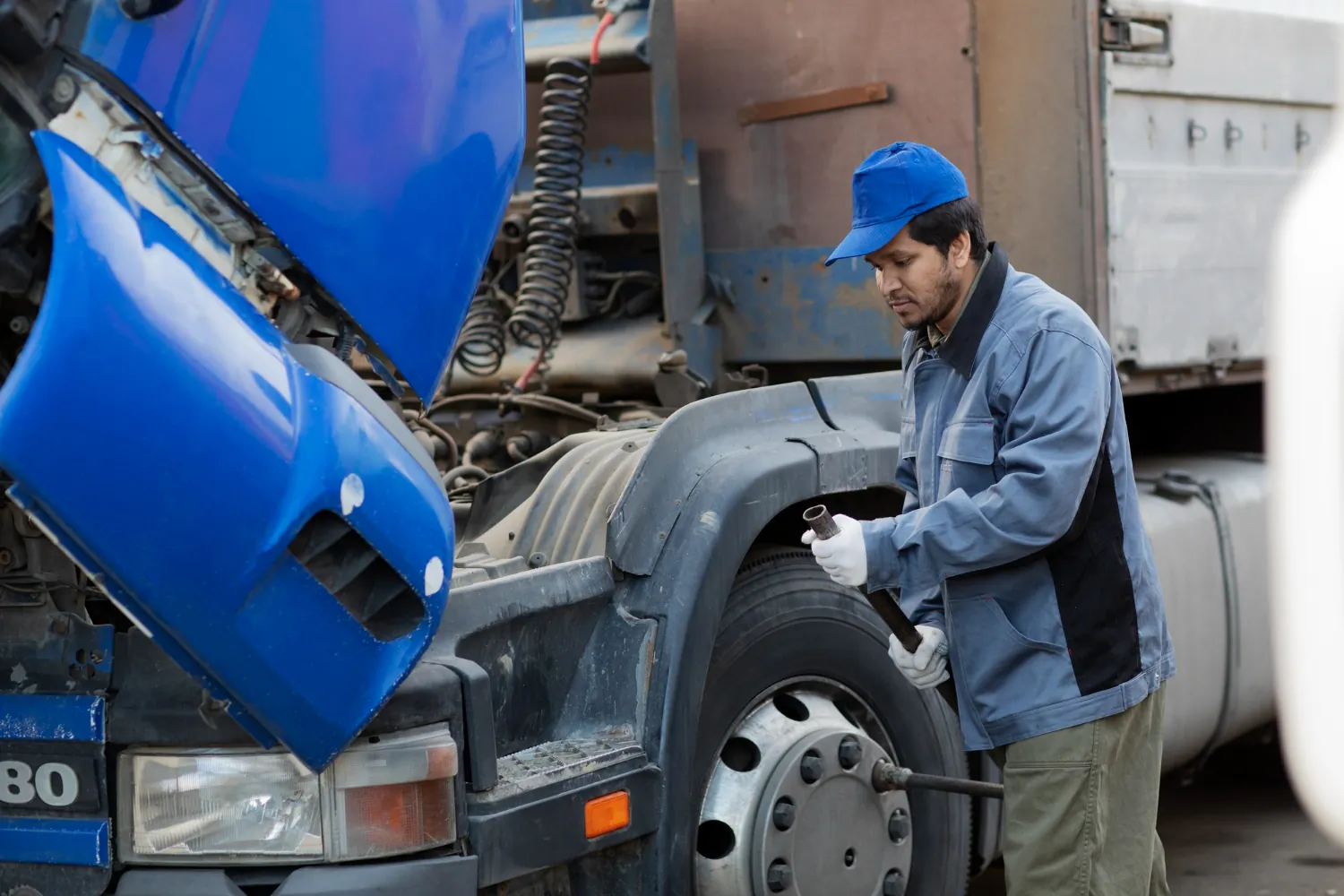 A mechanic conducting maintenance on a truck's front wheel, an essential step in preventing accidents.