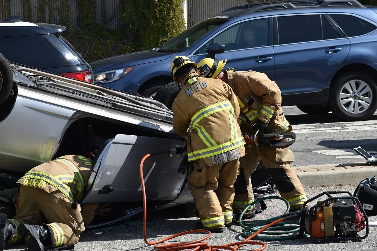 Firefighters using tools to assist in a rescue from an overturned car on the road