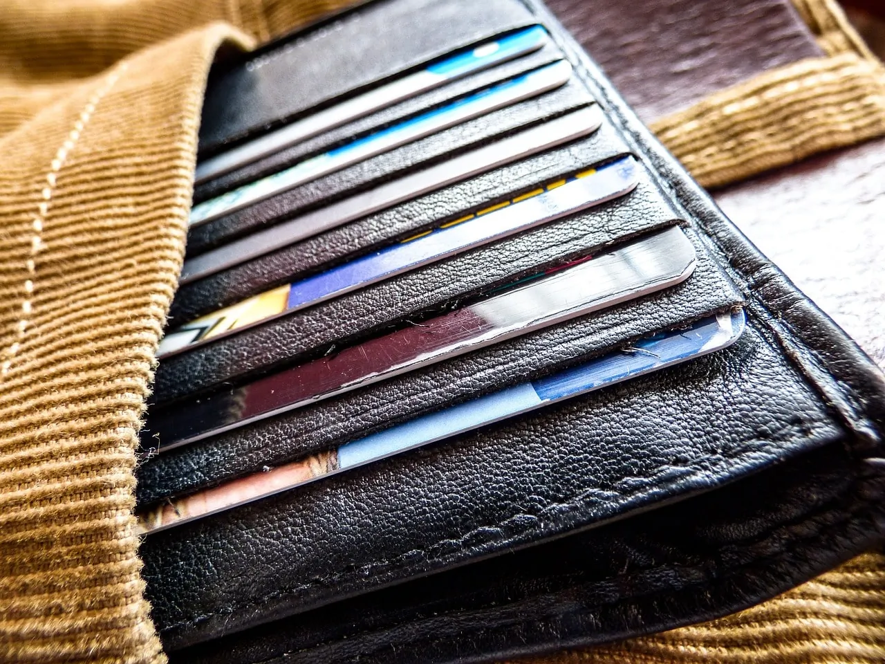 Close-up of a wallet filled with various credit cards, illustrating the burden of multiple debts and potential legal issues from being sued by a credit card company.