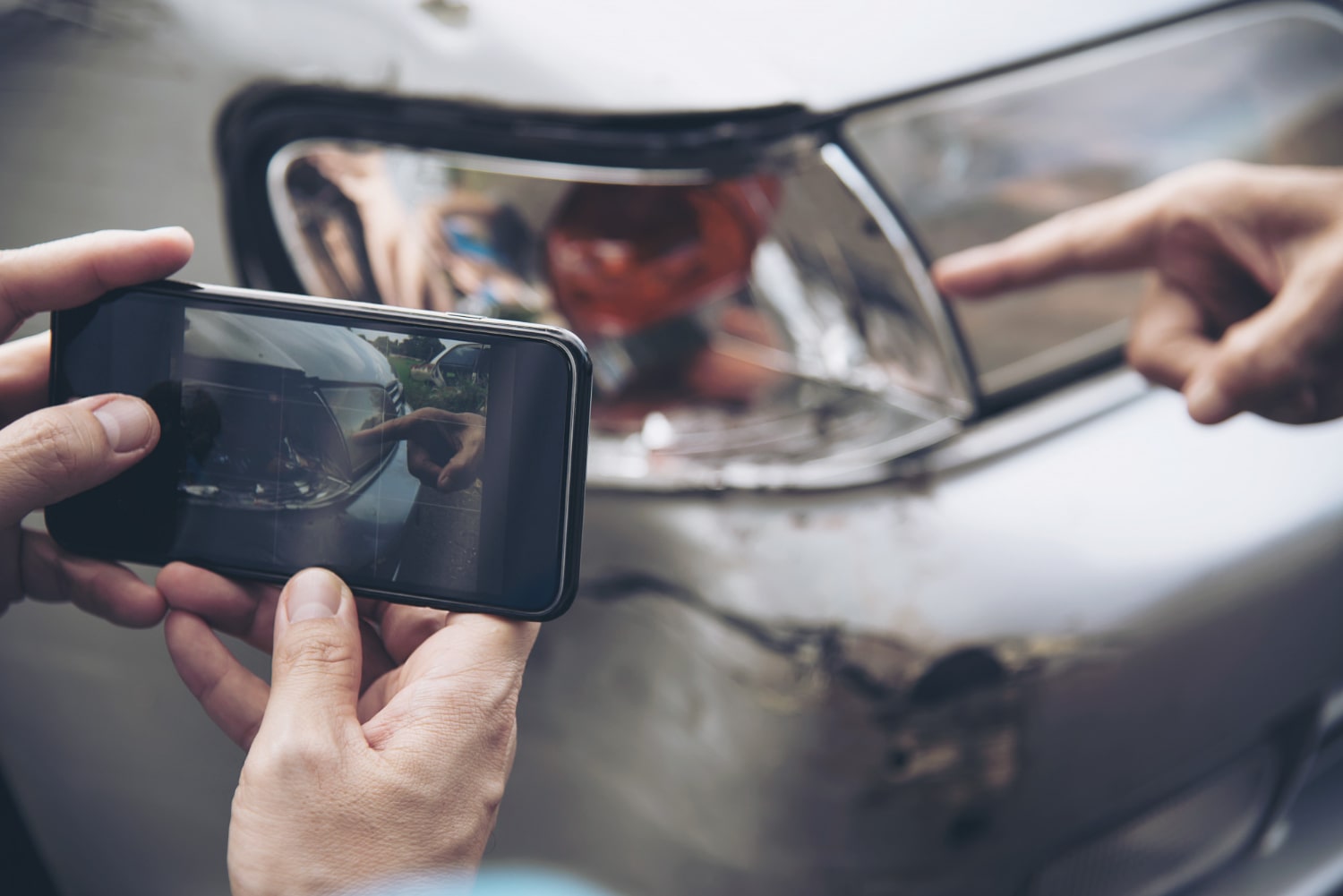 Person photographing car taillight damage with a smartphone for insurance claim evidence