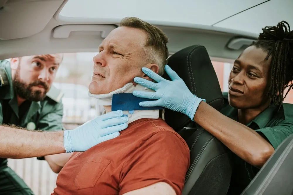 Paramedics assisting a man with a neck injury after a car accident, ensuring his safety and comfort.