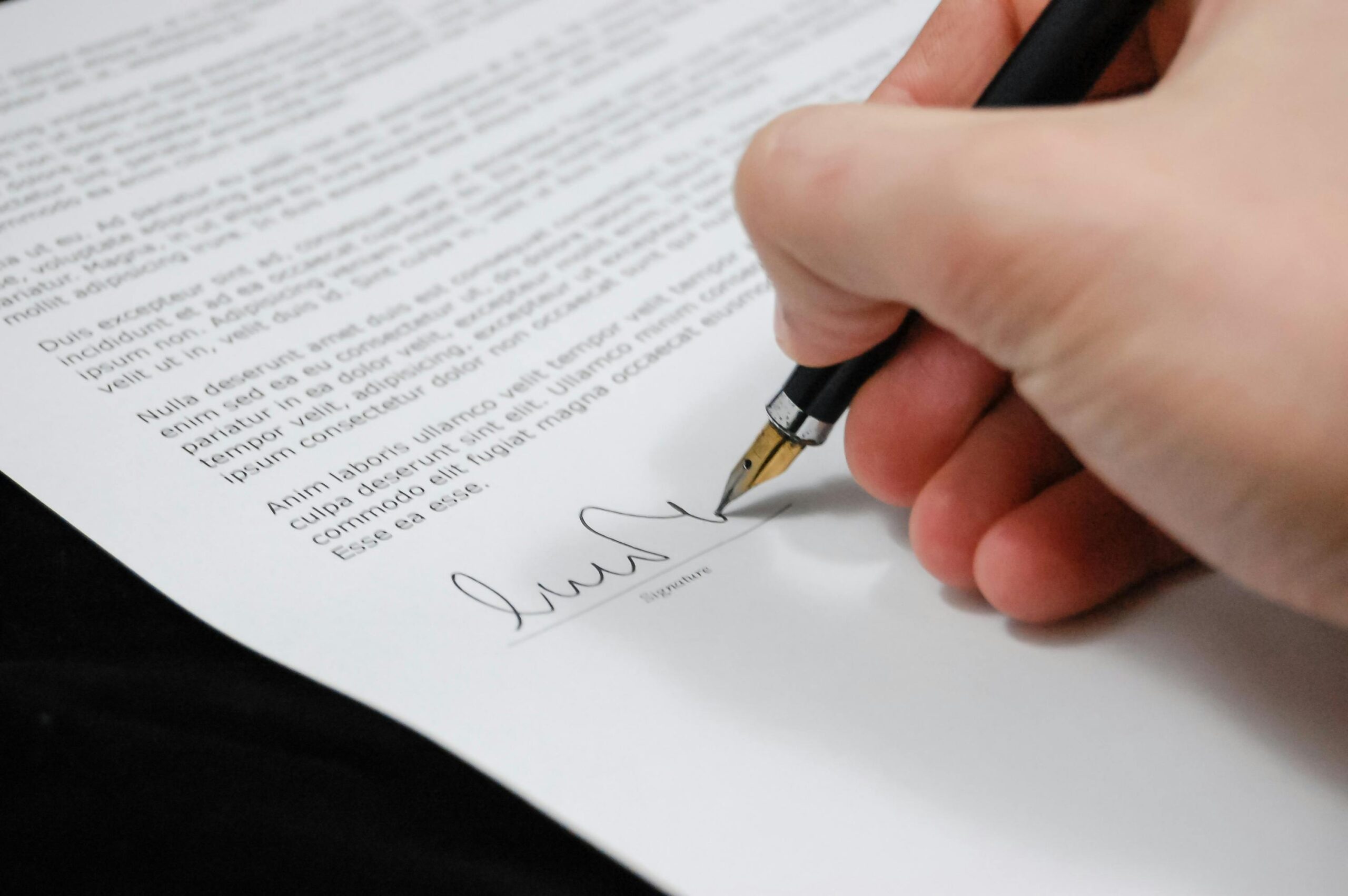 A hand signing a legal document, highlighting the importance of official agreements in wrongful death cases.