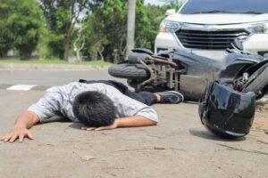 Injured man lying beside motorcycle on roadway after traffic accident