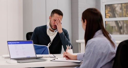 injured worker wearing neck brace and arm sling during Health Insurance Claim meeting