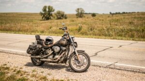 worn cruiser motorcycle with helmet and saddlebags parked on rural roadside