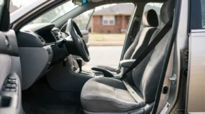 car interior showing front seat with seatbelt, steering wheel, and dashboard
